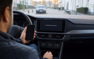 Fahrer prüft im geparkten Auto ein per USB angeschlossenes Smartphone, während das Infotainment keine Verbindung meldet.