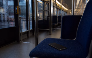 Ein vergessenes Smartphone liegt auf einem leeren Sitz in einer Straßenbahn