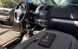 Heißes Smartphone mit pausiertem Ladevorgang und abgezogenem USB-C-Kabel im geparkten Auto